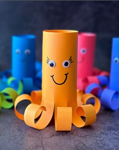 Image of the paper roll octopus craft. the example is orange with 3 in the background.